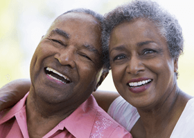 Elderly couple smiling with their heads leaning against each other