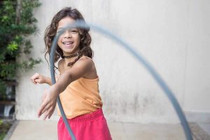 young girl playing with a hula hoop and smiling