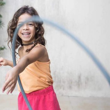 young girl playing with a hula hoop and smiling